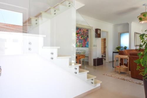 ein Wohnzimmer mit einer weißen Treppe in einem Haus in der Unterkunft Hide&Sea Aroeira villa w/ heated pool at the Beach in Aroeira