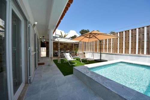 a swimming pool with an umbrella on a building at Aroeira villa with heated pool by Golf course, Beach and Lisbon in Aroeira