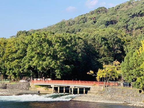a red bridge over the water with a mountain at Hanayashiki Ukifune-en in Uji
