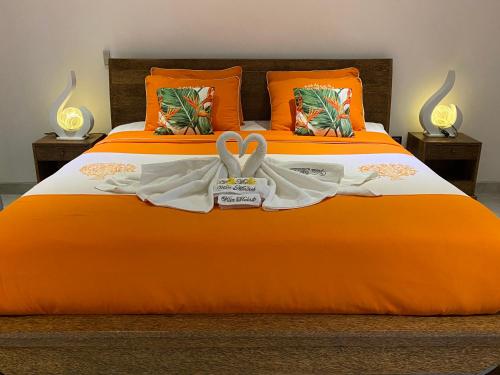 an orange bed with two white towels on it at Villa Mabuk in Legian