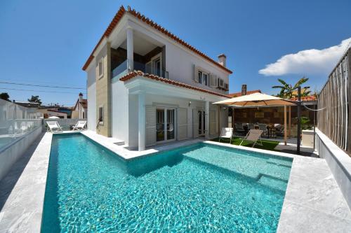 a villa with a swimming pool in front of a house at Aroeira villa with heated pool by Golf course, Beach and Lisbon in Aroeira