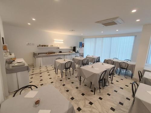 a restaurant with white tables and chairs and a kitchen at Hotel Exclusive in Riccione