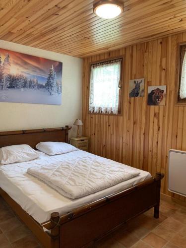 une chambre avec un grand lit dans une pièce en bois dans l'établissement Chalet- Capacité 8/10 pers au cœur de la station, à Besse-et-Saint-Anastaise