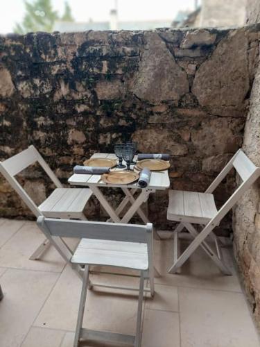 une table et des chaises installées à côté d'un mur en pierre dans l'établissement La petite maison bleue, à Mouret