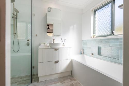 a white bathroom with a sink and a shower at 32 Beachside - LJHooker Yamba in Yamba