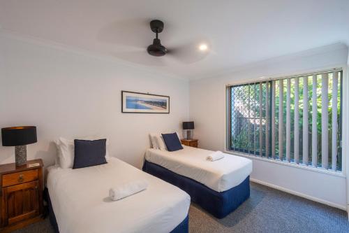 dwa łóżka w pokoju z oknem w obiekcie 32 Beachside - LJHooker Yamba w mieście Yamba