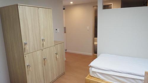 a bedroom with a bed and a large wooden cabinet at Hannah Guesthouse in Jeju