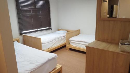 two beds in a small room with a window at Hannah Guesthouse in Jeju