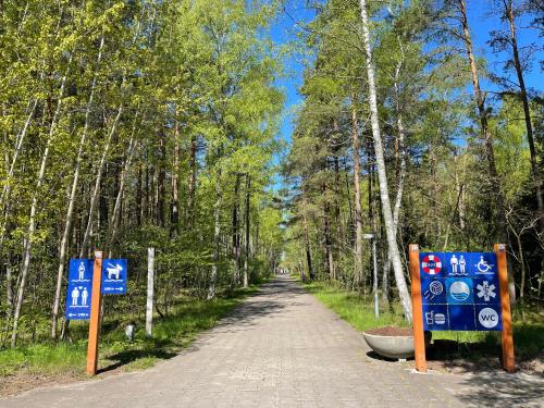 a dirt road in a forest with signs on it at Nida family apartments in Nida