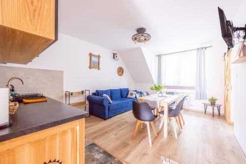 eine Küche und ein Wohnzimmer mit einem blauen Sofa und einem Tisch in der Unterkunft Czarna Góra Apartamenty TATRY GÓRY BIAŁKA T BUKOWINA T ZAKOPANE in Czarna Góra