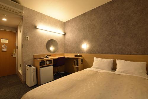 旭川市にある旭川サンホテルの大きなベッドとデスクが備わるホテルルームです。