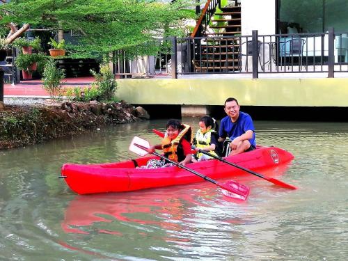 a man and two children in a red kayak in the water at Saithong Resort in Pak Meng