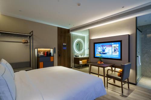 um quarto com uma cama grande e uma televisão em UrCove by HYATT Futian CBD em Shenzhen