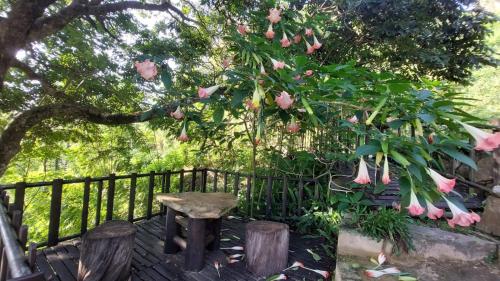 una cerca con un banco y un árbol con flores rosas en Brisk Ella Retreat en Ella