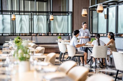a group of people sitting at tables in a restaurant at Crowne Plaza Phu Quoc Starbay by IHG in Phu Quoc