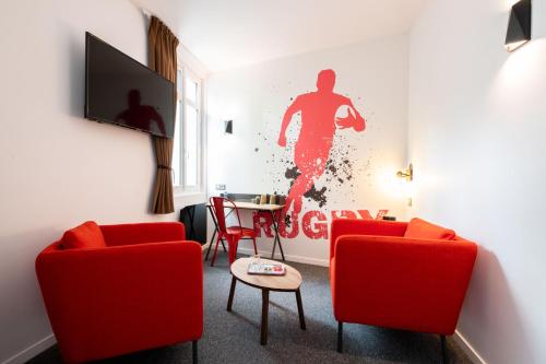 a living room with two red chairs and a painting of a man at Urban Style Biarritz Le Relais in Biarritz