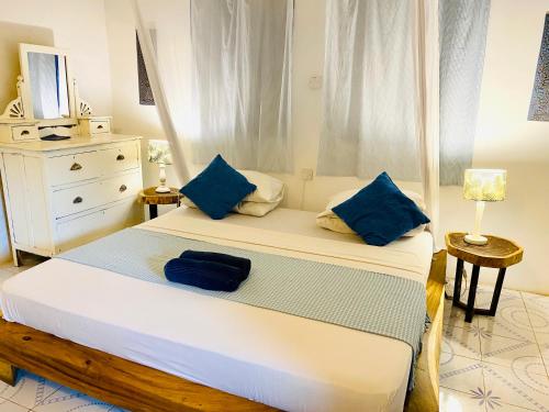 a bedroom with a large bed with blue pillows at Badolina Bungalows in Nungwi