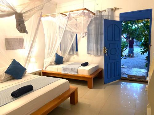 a bedroom with two beds and a blue door at Badolina Bungalows in Nungwi