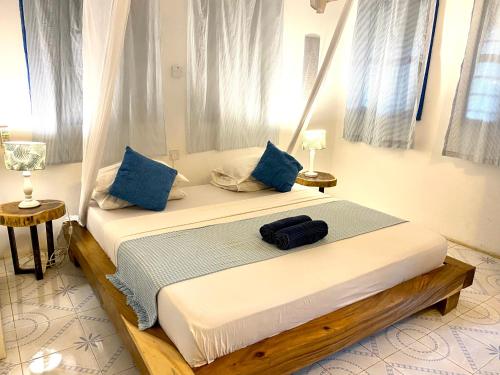 a bedroom with a large bed with blue pillows at Badolina Bungalows in Nungwi