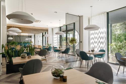 un ristorante con tavoli, sedie e finestre di SZUMY PARK Hotel & Restaurant a Susiec