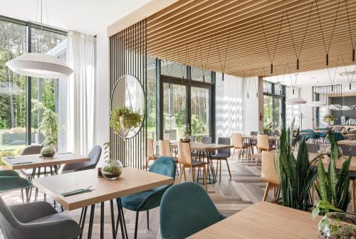 a restaurant with tables and chairs and windows at SZUMY PARK Hotel & Restaurant in Susiec
