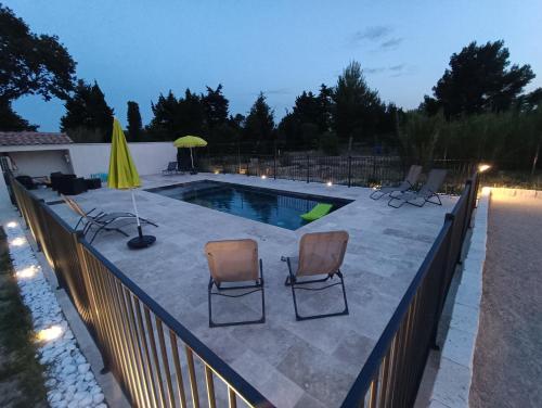 uma piscina com três cadeiras e um guarda-sol amarelo em Maison indépendante avec piscine, 10min Avignon em Pujaut