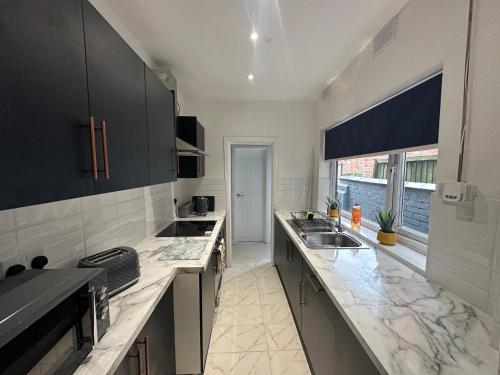 a kitchen with black cabinets and marble counter tops at Westwood Place in Spon End