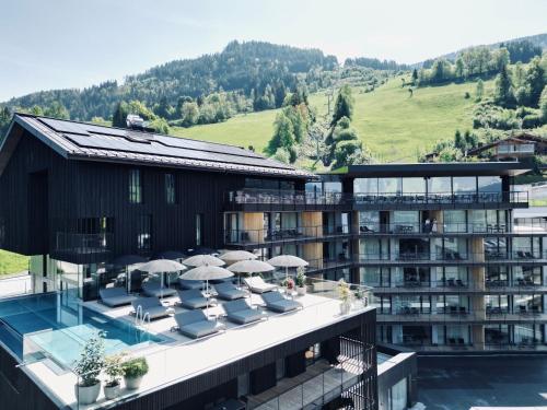 ein Hotel mit einem Balkon mit Stühlen und Sonnenschirmen in der Unterkunft Haven Mountain Retreat in St. Johann im Pongau