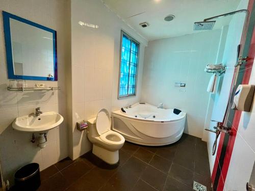 a bathroom with a tub and a toilet and a sink at Eight Days Boutique Hotel - Impian Emas in Skudai