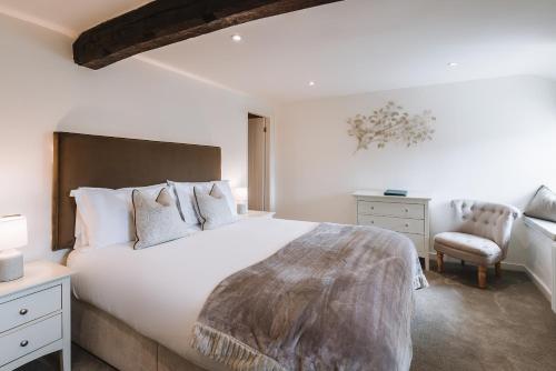 a bedroom with a large white bed and a chair at Coffee & Stays at Cartmel Square in Cartmel