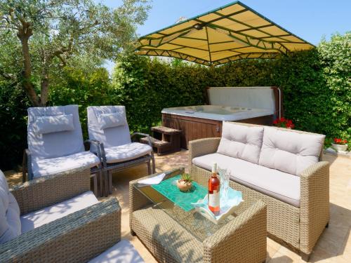 eine Terrasse mit 2 Stühlen, einem Sofa und einem Sonnenschirm in der Unterkunft Holiday Home Nevena in Buje