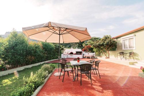 a patio with a table and chairs and an umbrella at Greek Style Apartment with Jaquzzi & Barbeque in Triánta