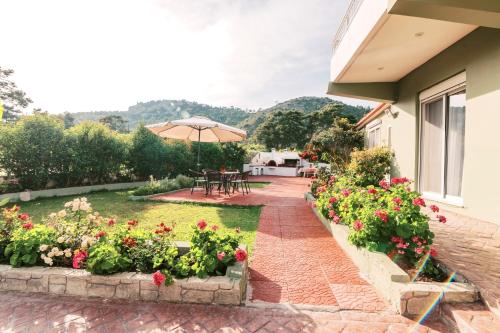 a garden with flowers and a patio with an umbrella at Greek Style Apartment with Jaquzzi & Barbeque in Triánta