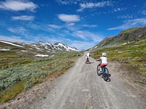 two people riding bikes down a dirt road at New, Mountain paradise, fishing, biking, mountaineering in Tyinkrysset