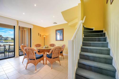 a staircase in a house with a table and chairs at 11 Vesta Dve - BYO Linen - Waterfront in Hindmarsh Island
