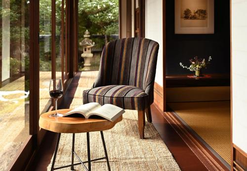 a chair and a table with a book and a glass of wine at Casa Miyama in Nantan city