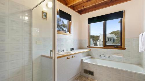 uma casa de banho com um chuveiro, uma banheira e um lavatório. em Wrens View em Dinner Plain