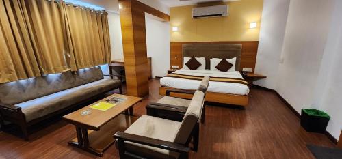 um quarto de hotel com uma cama e um sofá em Hotel Kanak em Ahmedabad