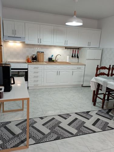 a kitchen with white cabinets and a table and a rug at Villa Leah Apartment in Yerakiní