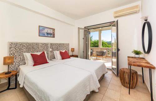 Villa Georgia في Ágios Stéfanos: غرفة نوم مع سرير أبيض كبير مع وسائد حمراء