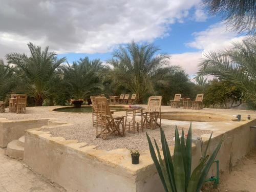 een groep stoelen en tafels op een binnenplaats bij Al Kahina Gardens, Retreat and Resort in Siwa