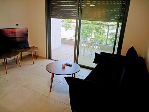 a living room with a couch and a table and a television at Agamim Park Residence in Ashqelon