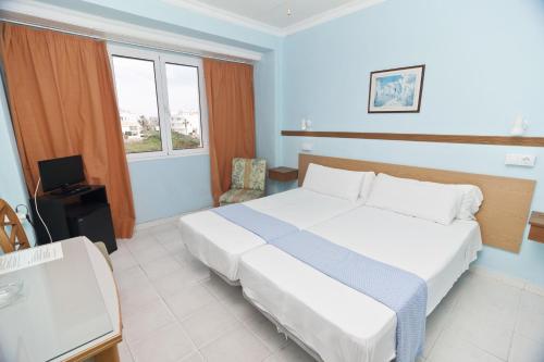 
a hotel room with a bed and a television at Cala Bona y Mar Blava in Ciutadella
