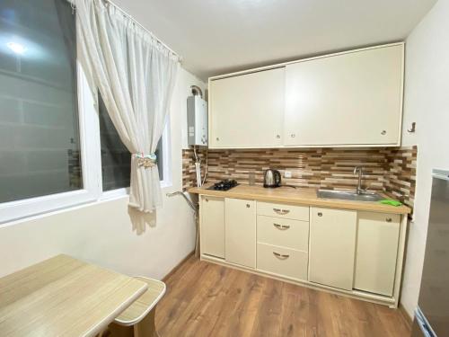 a kitchen with white cabinets and a table and a window at Freedom Square apartment in Tbilisi City