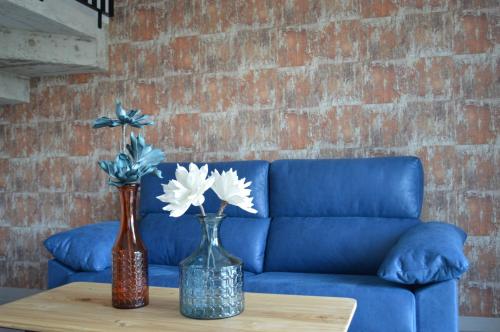 two vases on a table in front of a blue couch at O Cabanel de Pepe in Muxia