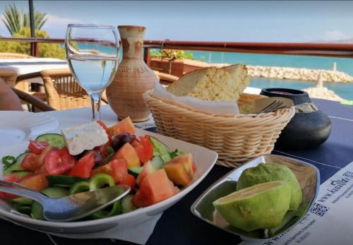 a table with a plate of food and a glass of wine at Shambala Beach House-where mountains meet the sea in Pomos