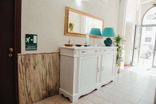 布林迪西的住宿－都靈酒店，一间带镜子和白色橱柜的浴室