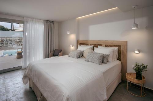 a bedroom with a large white bed and a bathroom at Anassa Suites Stalis by Estia "Adults Only" in Stalida