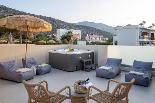 a patio with a hot tub and chairs and an umbrella at Anassa Suites Stalis by Estia "Adults Only" in Stalida
