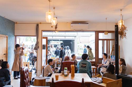 a group of people sitting at tables in a restaurant at 暮らす実験室 in Taketa